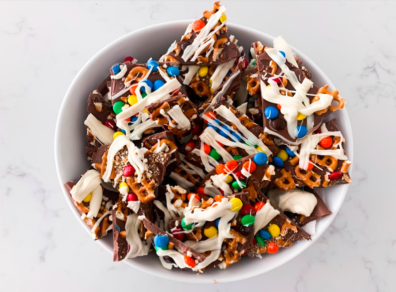 Popular Lifestyle and Beauty Blogger, Kelly Snider, shares an easy Chocolate Bark Recipe; Image of a bowl of chocolate bark with m&ms and pretzels.