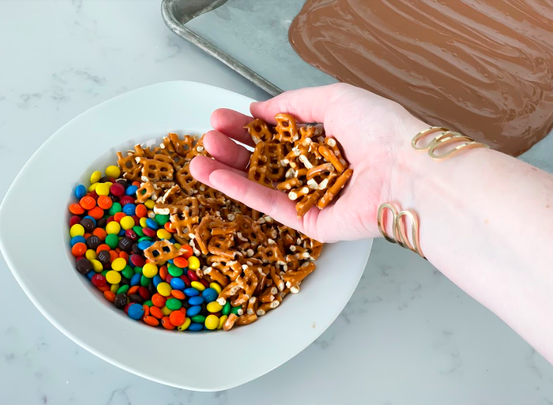 Popular Lifestyle and Beauty Blogger, Kelly Snider, shares an easy Chocolate Bark Recipe; Image of a bowl of mimi m&ms and crushed pretzels. 
