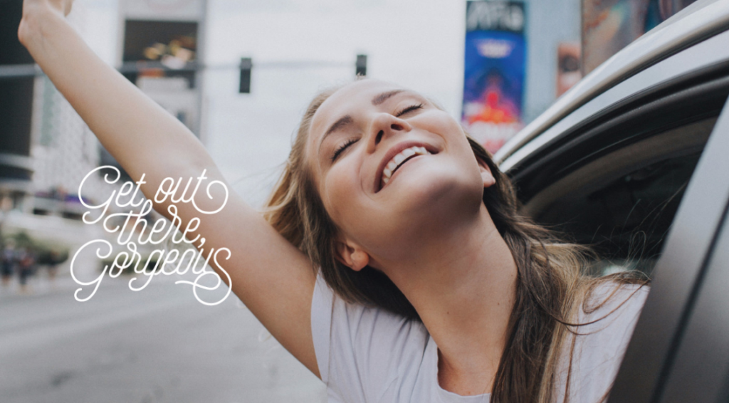 Sell Makeup From Home by popular Utah beauty blogger, Kelly Snider: image of a woman leaning out the passenger window in a car and holding her hand above her head. 