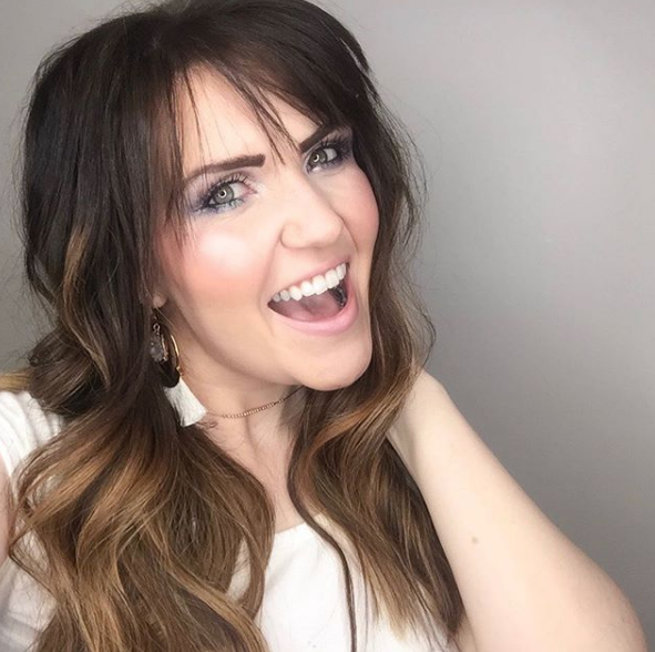 How to Make Money as a Beauty Blogger by popular Utah beauty blogger, Kelly Snider: image of Kelly Snider wearing purple eye makeup, white tassel earrings, and doing a open mouth smile.
