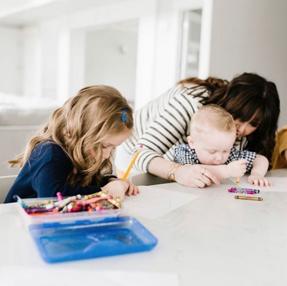 Stay at Home Makeup by popular Utah beauty blogger, Kelly Snider: image of a woman coloring with her kids at their kitchen island counter.