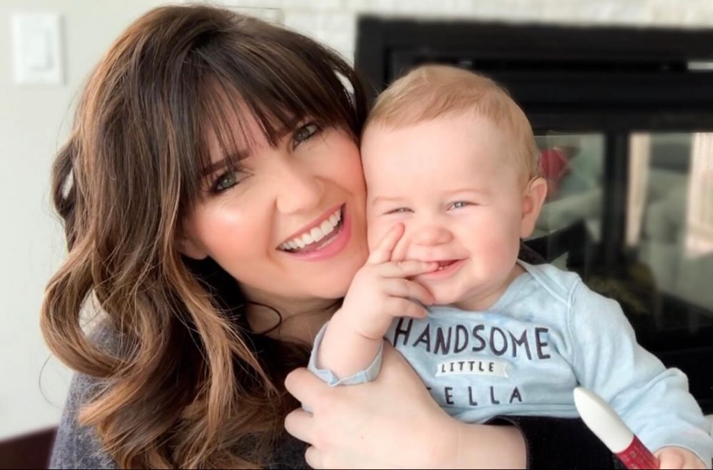 Popular Utah Blogger and Independent Maskcara Artist, Kelly Snider addresses MLM jobs for stay-at-home moms; image of smiling mom holding a smiling baby. 