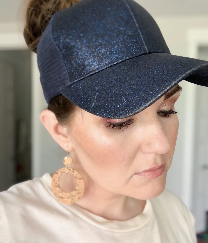 Messy Bun Hats - The best fifth day hair hack by Popular Utah Blogger and Top Maskcara Beauty Artist, Kelly Snider; image of woman wearing a navy blue sparkly messy bun hat with cork hoop earrings.