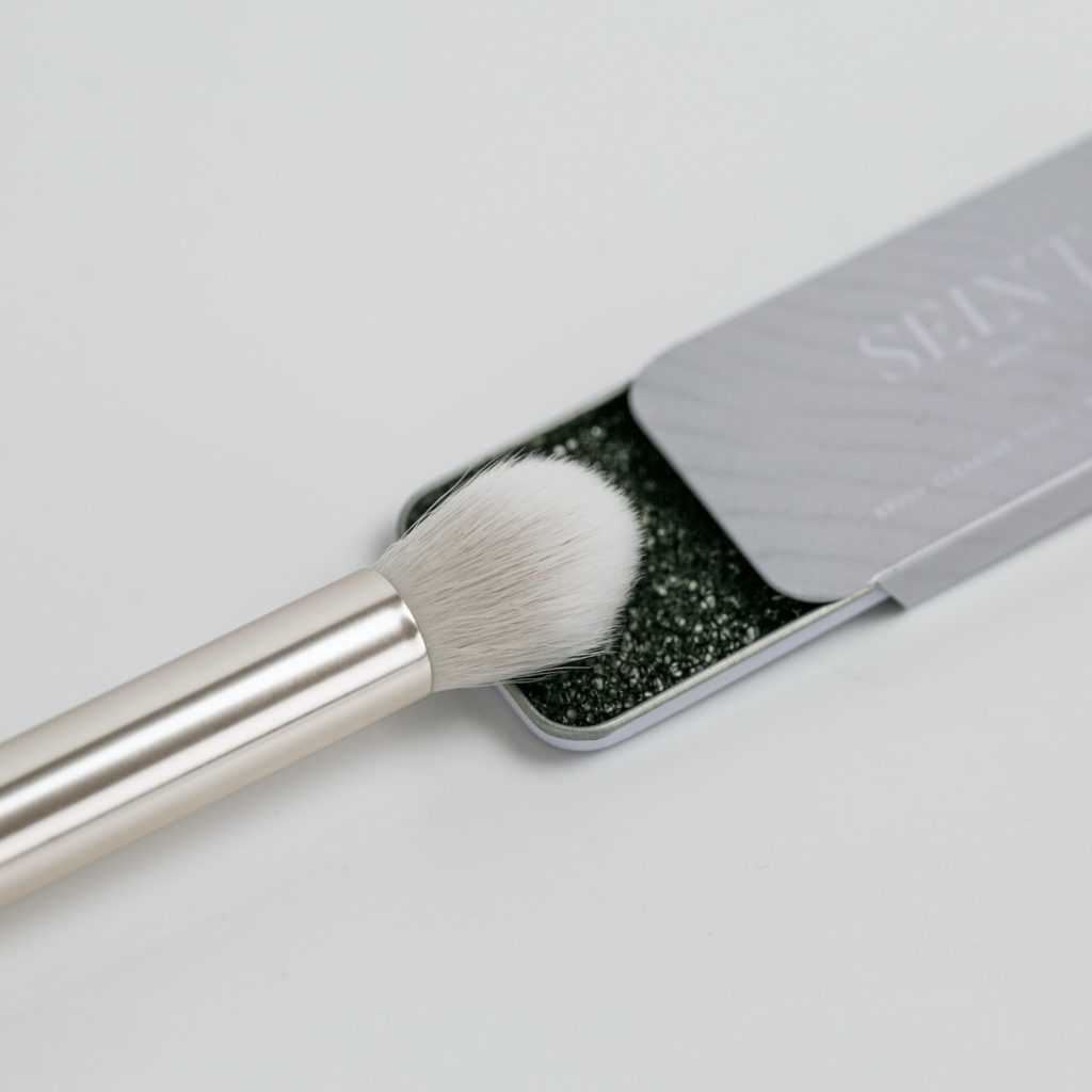 Up close picture of Seint eyeshadow and eyeshadow brush. 